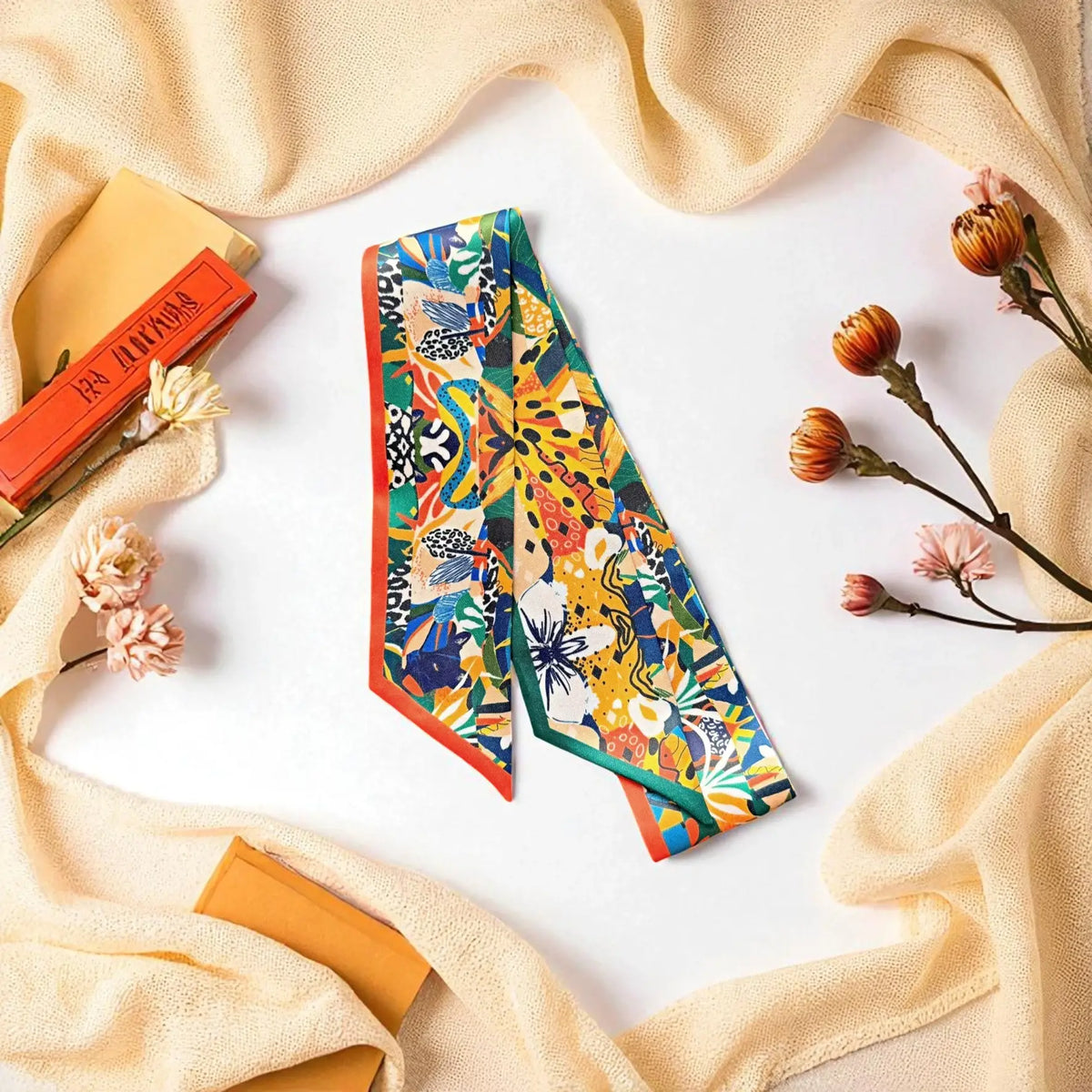 Satin twilly scarf showcasing an artistic jungle-inspired pattern with tropical vegetation, geometric accents, and animal-print details, arranged in a lively multicoloured composition.
