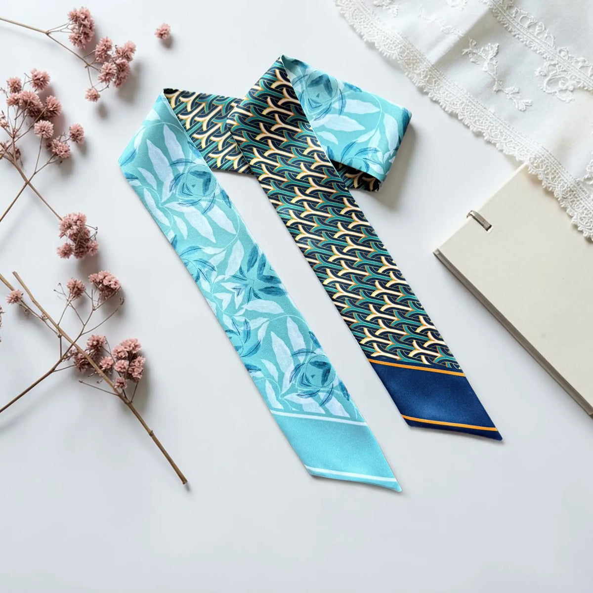 Blue twilly scarf featuring soft floral motifs paired with an elegant navy and gold geometric pattern.