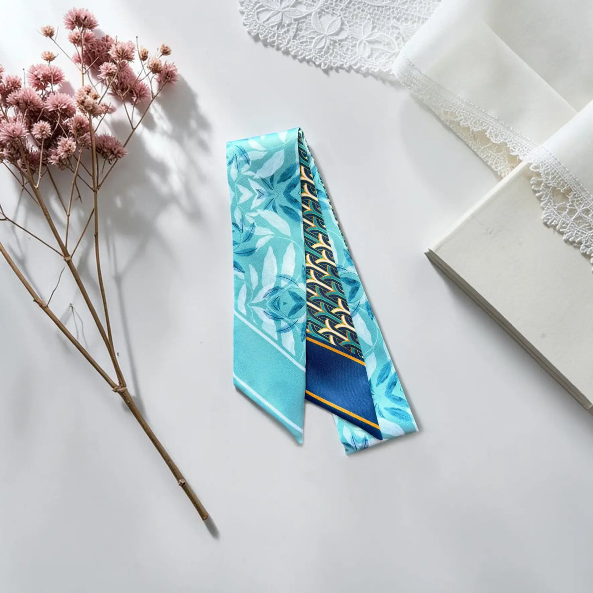Blue skinny scarf featuring graceful floral illustrations, aqua tones, and an intricate navy geometric pattern.