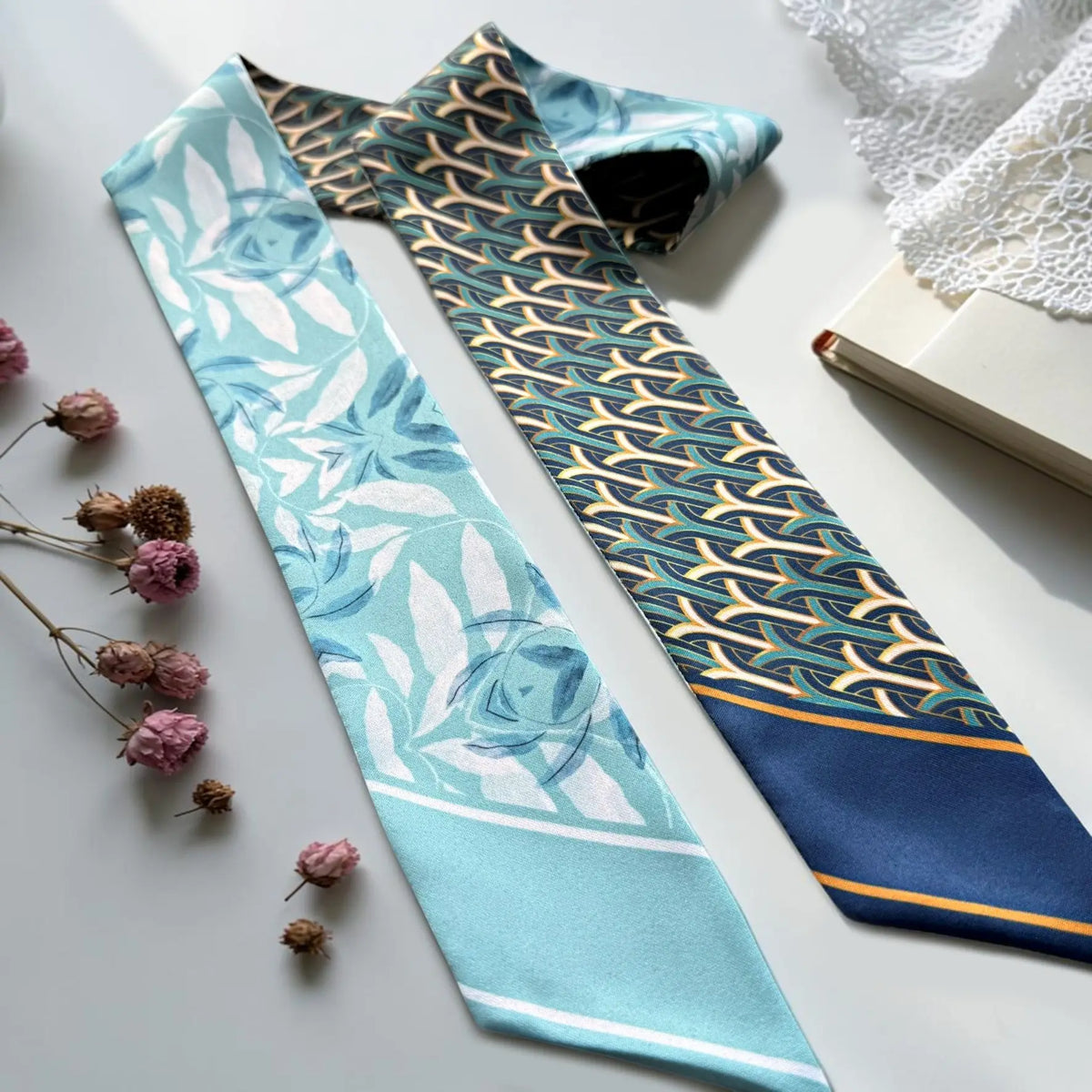 Elegant skinny bag scarf with aqua botanical florals and contrasting navy geometric motifs with gold accents.