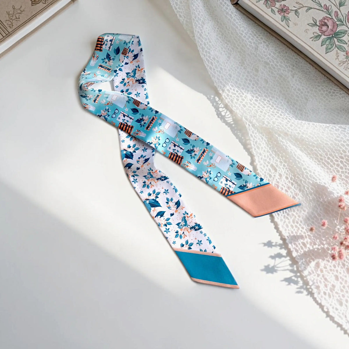 Personalized twilly scarf with blue and peach back-to-campus illustrations, floral details, books, glasses, and stationery motifs.