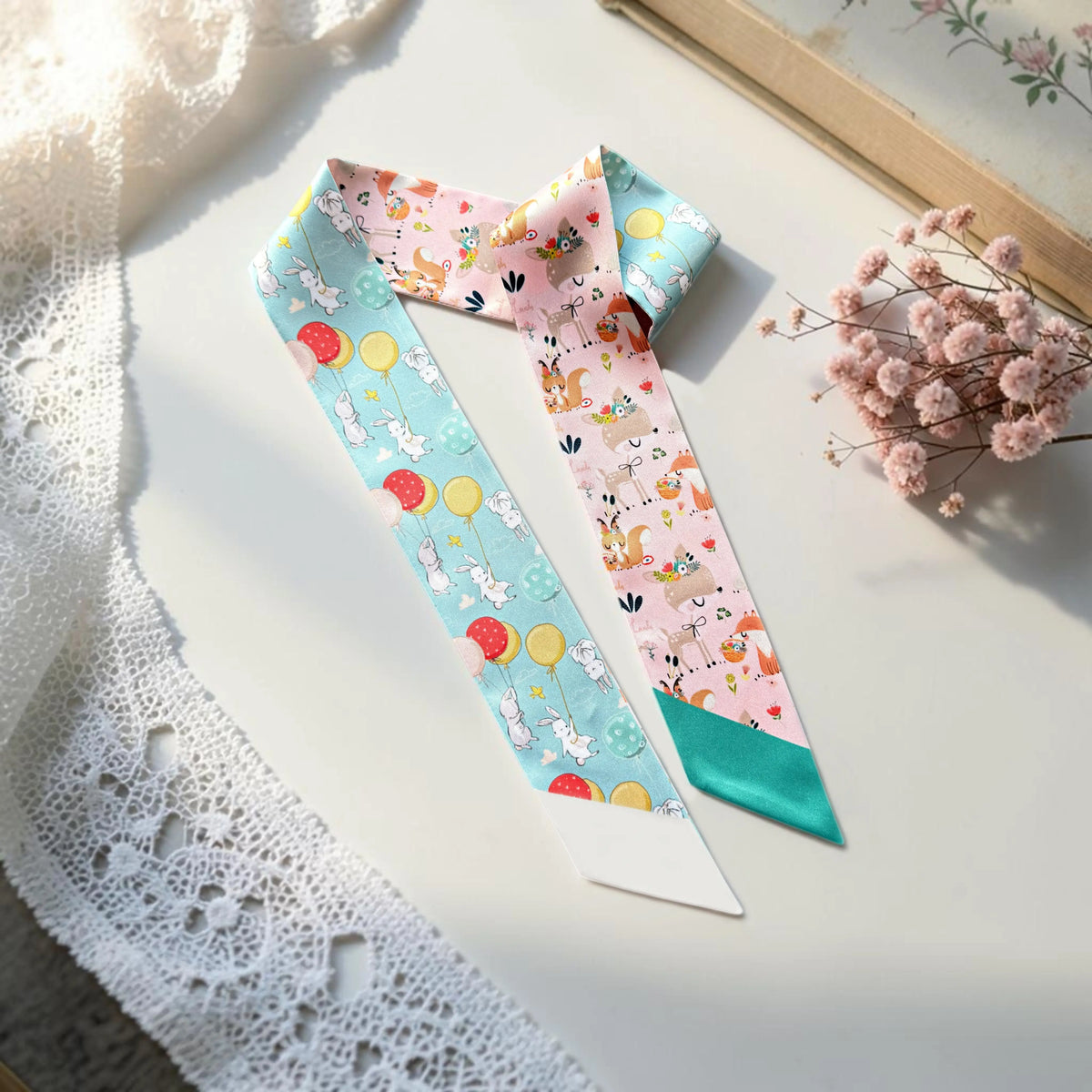 Whimsical twilly scarf featuring playful bunnies, woodland animals, colourful balloons, and soft pastel blue and pink backgrounds.