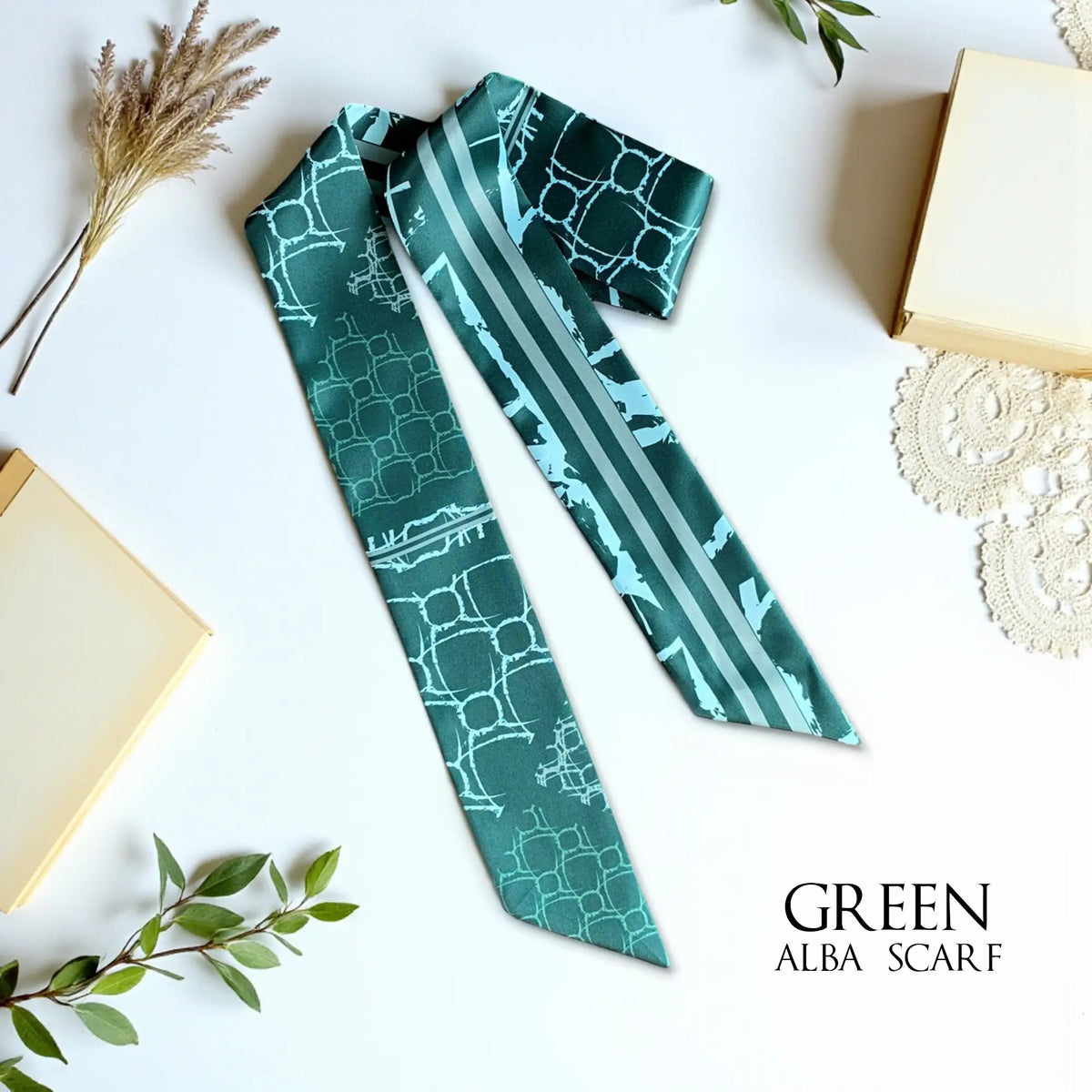 Emerald green monochrome twilly scarf featuring mint green geometric patterns and contrasting stripes, styled with dried botanicals.