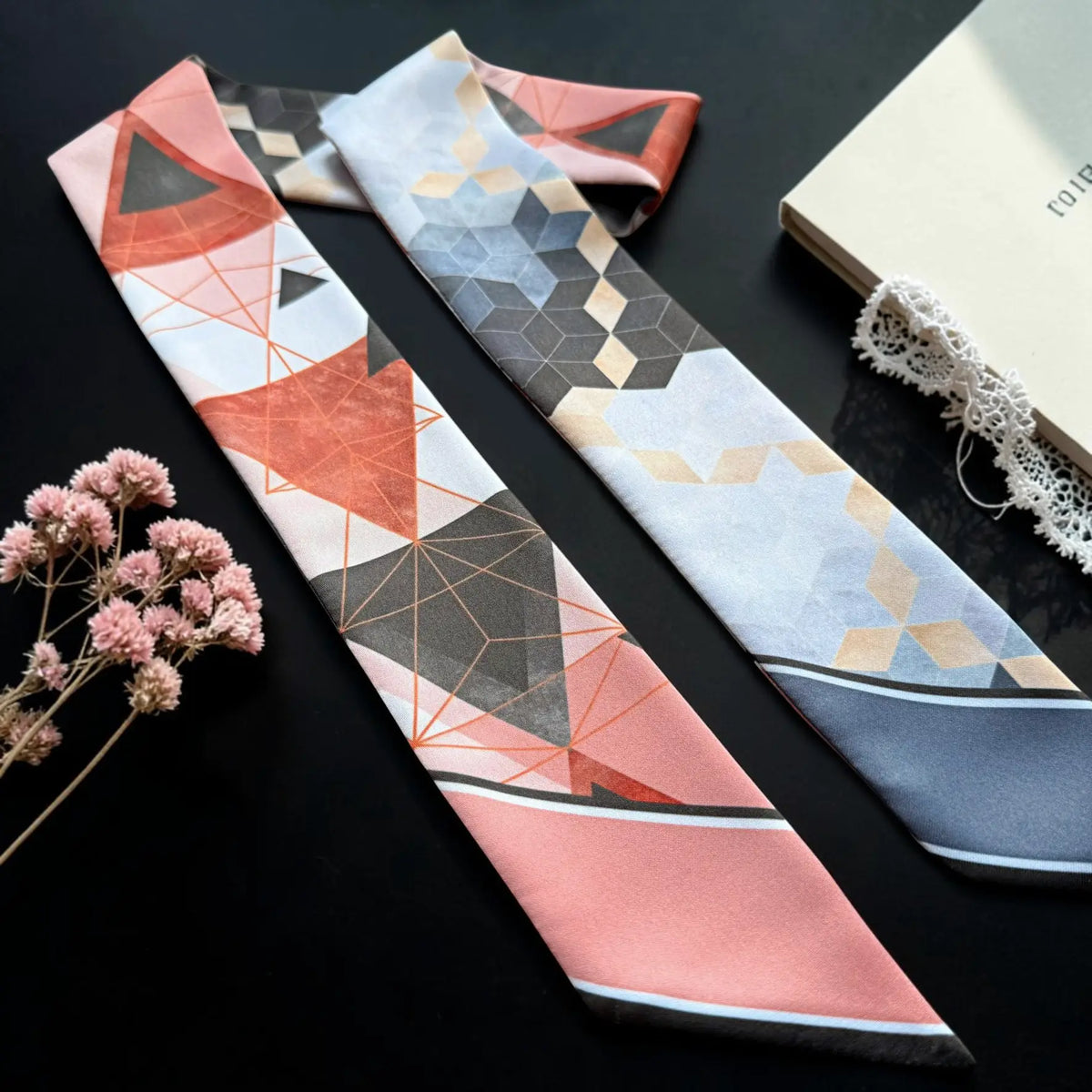 Slate blue satin twilly scarf featuring repeating hexagonal shapes, three-dimensional cube patterns, and soft beige accents, with a personalised blue pointed end.