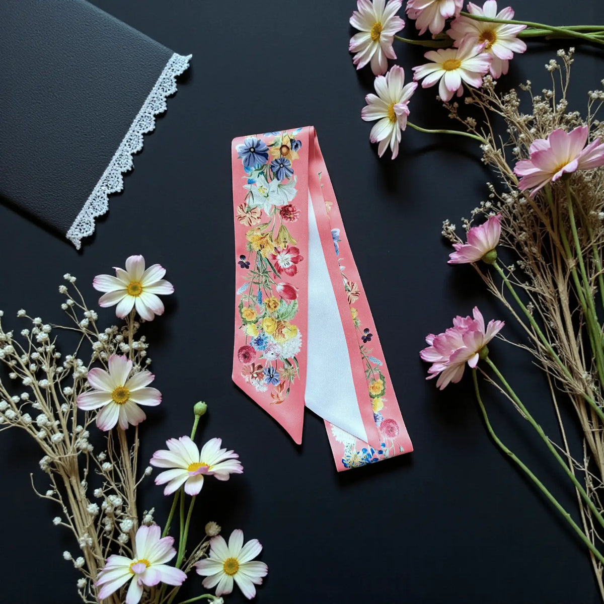 Personalised pink floral handbag scarf with a colourful botanical pattern and soft pink trim, styled with fresh white daisies.