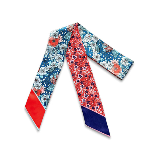 Colourful skinny scarf with vibrant red miniature floral prints and blue botanical illustrations featuring white, pink, and coral blossoms.