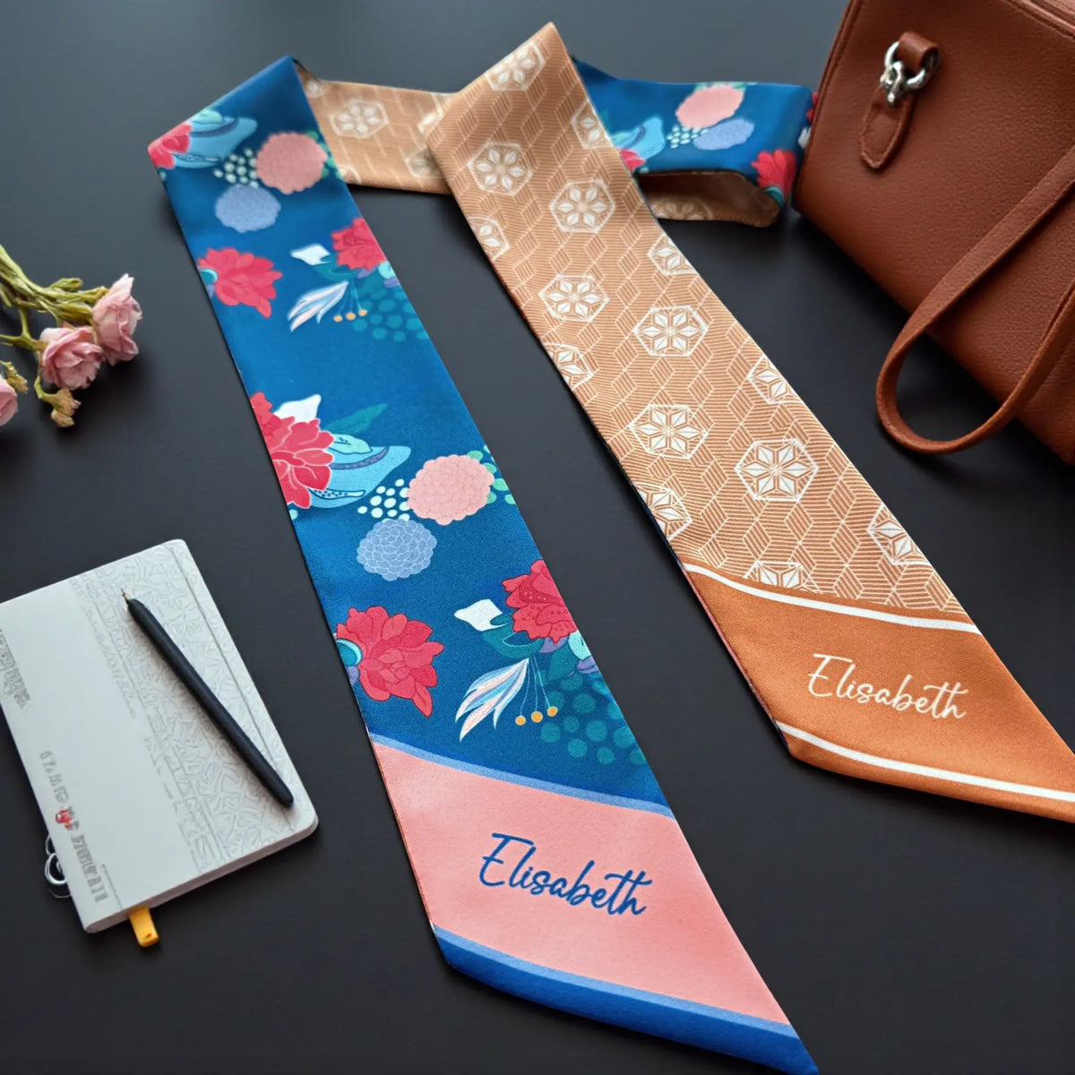 Personalised twilly scarf featuring an intricate tan and cream geometric pattern with repeating diamond-shaped motifs and an orange pointed end displaying the name Elisabeth.