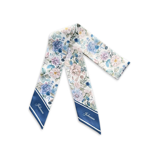 Elegant skinny scarf decorated with soft blue roses, dusty lavender blossoms, pale pink flowers, and intricate botanical leaves, displayed on a white background.