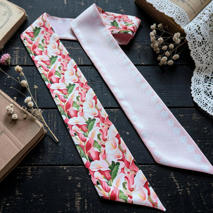 Botanical calla lily twilly scarf displayed with pink and ivory floral patterns against a dark background.