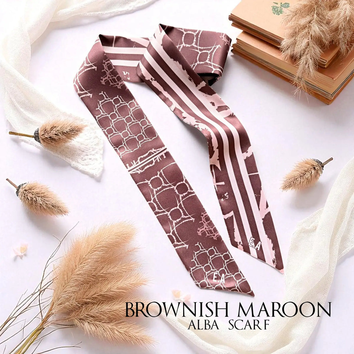 Brownish maroon monochrome skinny scarf featuring soft cream geometric patterns and elegant stripes, styled with dried botanicals and vintage books.