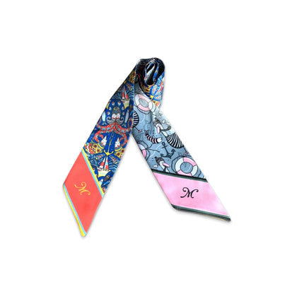 Rolled nautical twilly scarf showing colourful sailboat and marine-inspired patterns with contrasting patterned sides.