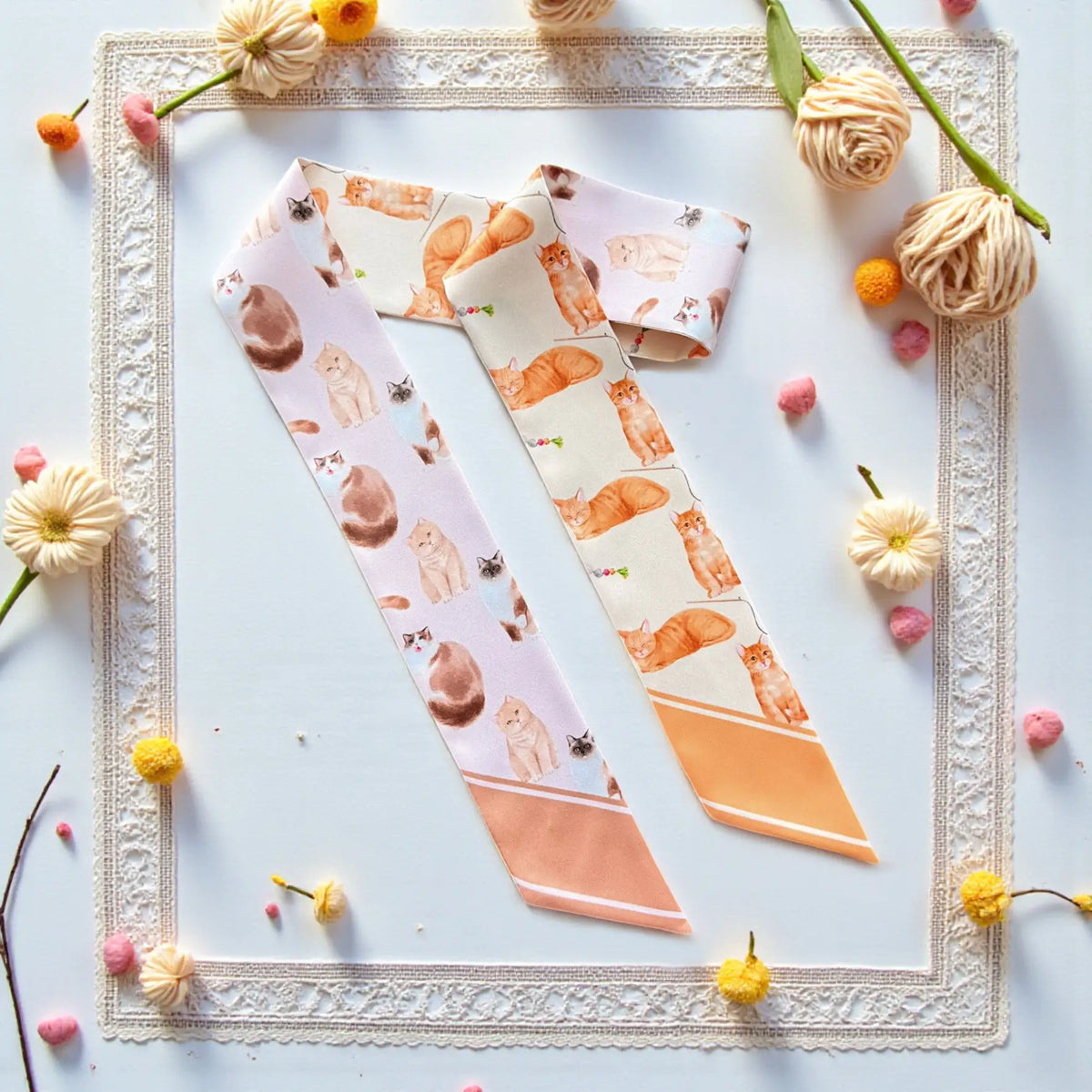 Cat lovers' twilly scarf featuring illustrated cats in soft pastel cream and warm orange tones.