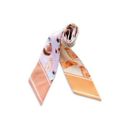 Rolled cat print twilly scarf showing assorted illustrated cats and contrasting peach-coloured pointed ends.