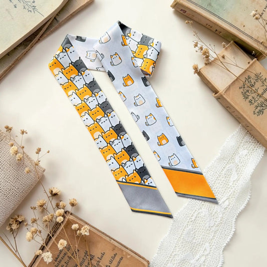 Cute cat print twilly scarf featuring playful orange, white and charcoal illustrated cats in repeating patterns.