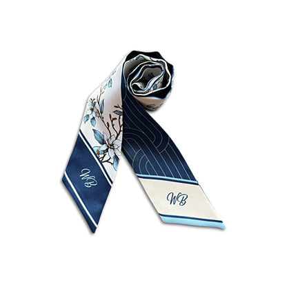 A rolled silk necktie featuring a navy blue and cream floral pattern with monogram initials 'WB' on the ends, displayed on a clean white background.