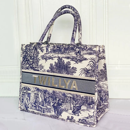 Structured personalized canvas book tote with embroidered name and blue Toile de Jouy countryside illustrations.