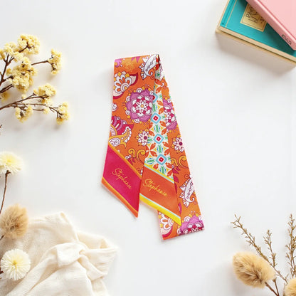 Vibrant handbag scarf with contrasting orange floral mandala prints and turquoise geometric designs, finished with personalized pink and coral pointed ends.