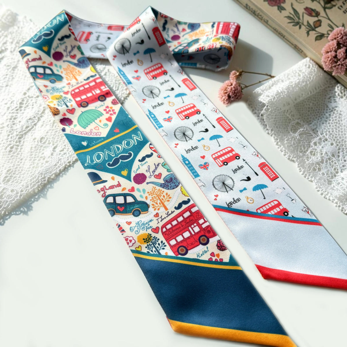 Whimsical London handbag scarf featuring vibrant British travel motifs, colorful decorative details, and contrasting navy blue and light blue pointed ends.