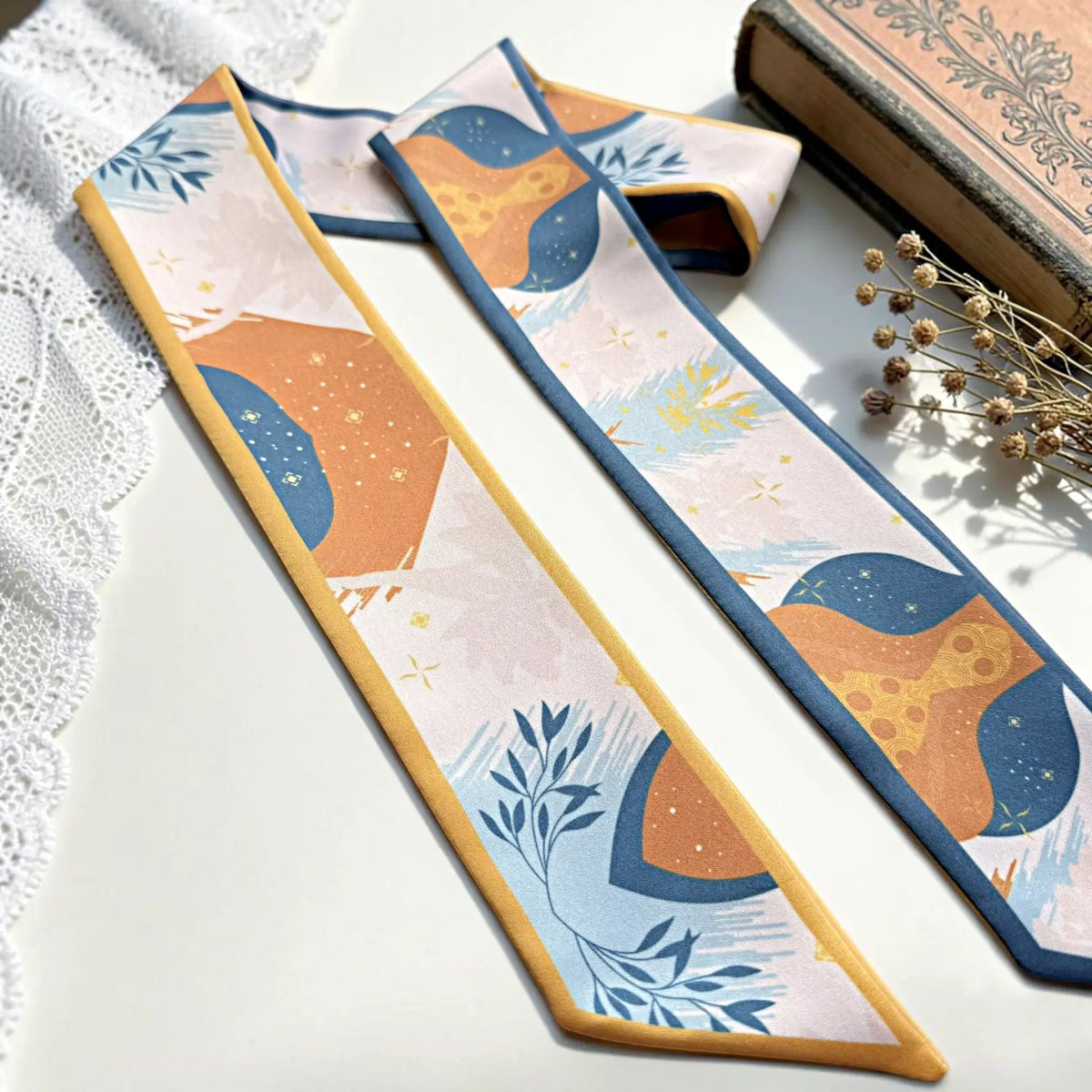 Colorful personalized skinny scarf with custom Molly lettering, featuring artistic orange and blue patterns, delicate floral motifs, and contrasting borders.
