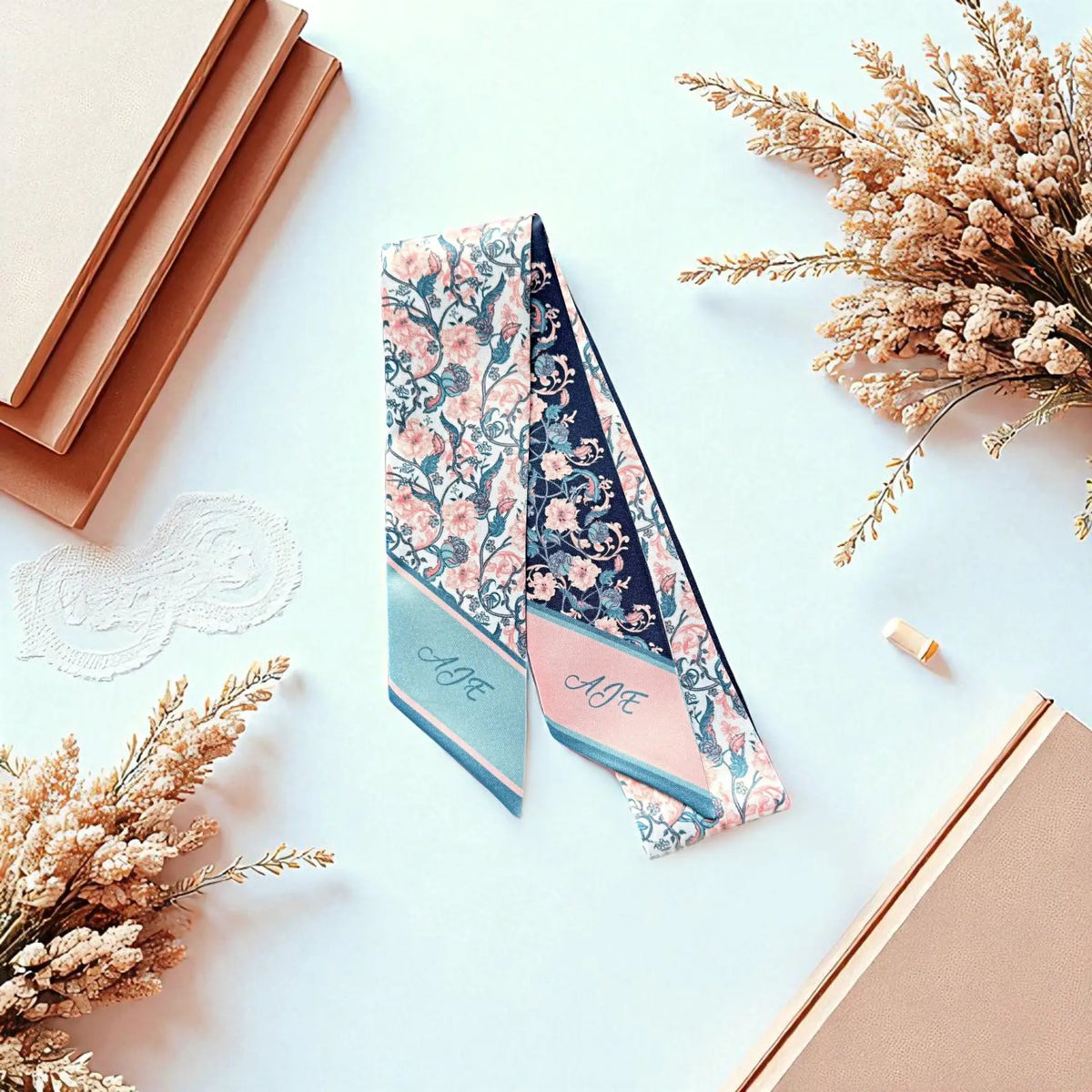 Elegant double-sided floral bag scarf showcasing contrasting navy and ivory backgrounds with coordinated pink botanical prints, displayed on a soft cream fabric backdrop.