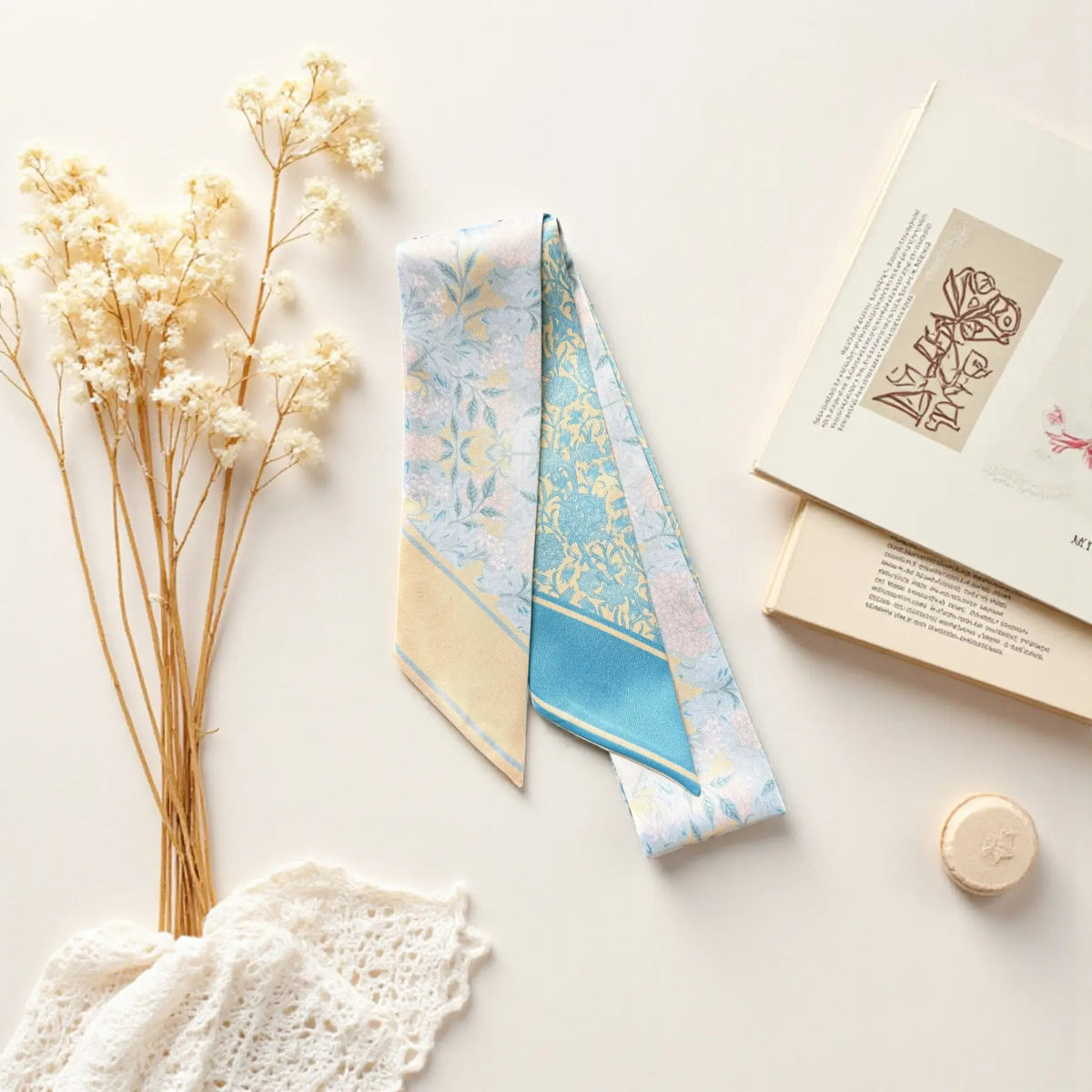 Elegant botanical twilly scarf in pastel blue and ivory displayed with dried flowers and stationery