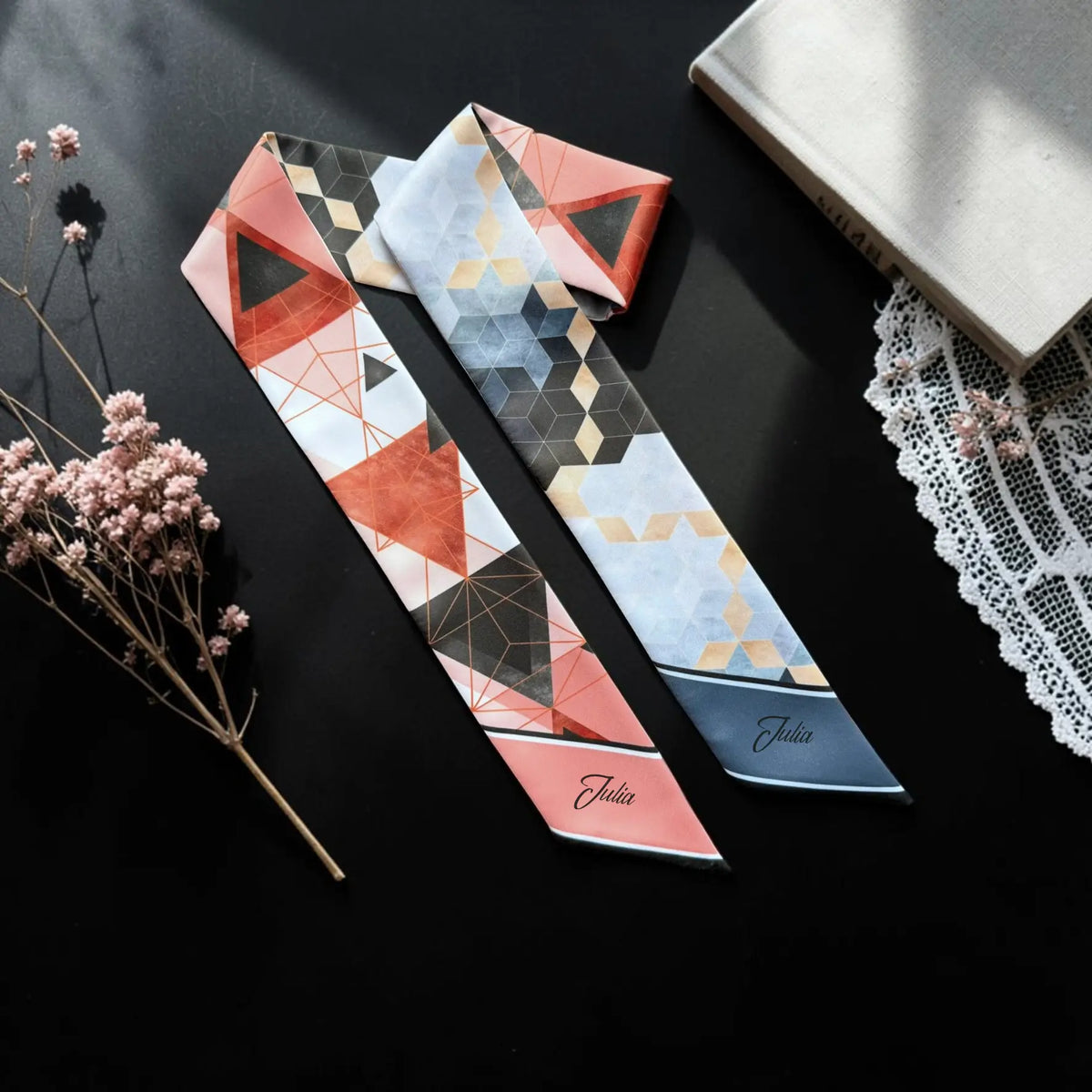 Personalised satin twilly scarf featuring contrasting abstract geometric patterns in coral pink, terracotta, slate blue, black, and beige, with the custom name Julia printed on both pointed ends.