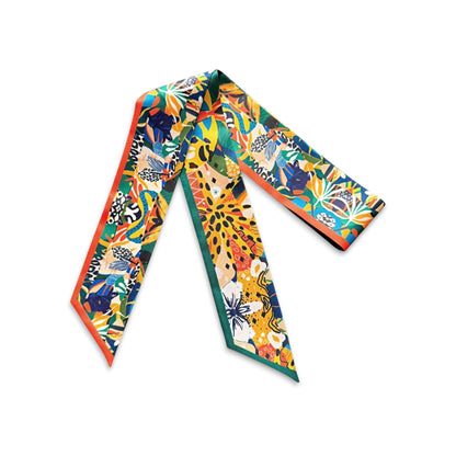Exotic botanical skinny scarf decorated with lush green leaves, bright orange and yellow floral motifs, and bold abstract details, finished with contrasting orange and green borders.
