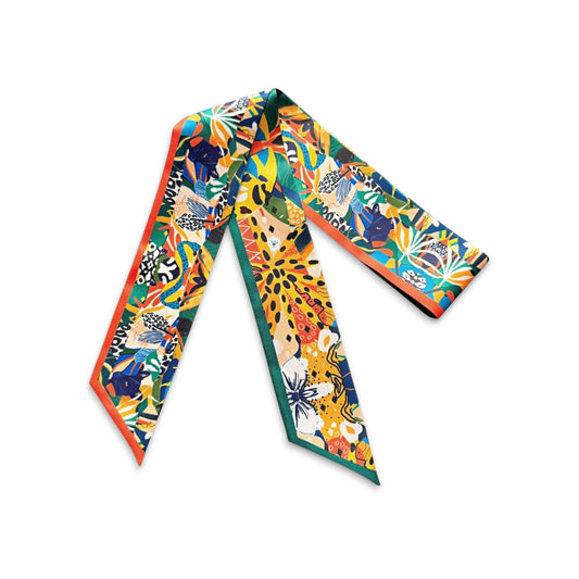 Exotic botanical skinny scarf decorated with lush green leaves, bright orange and yellow floral motifs, and bold abstract details, finished with contrasting orange and green borders.