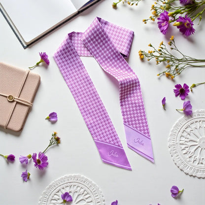 A purple-and-lavender houndstooth-patterned silk scarf with personalized names.