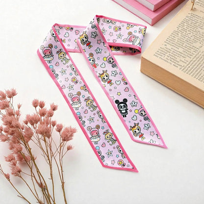 Close-up of a satin handbag scarf featuring a playful kawaii-inspired pattern with colourful cartoon characters, tiny stars, and hearts against a pastel pink background.