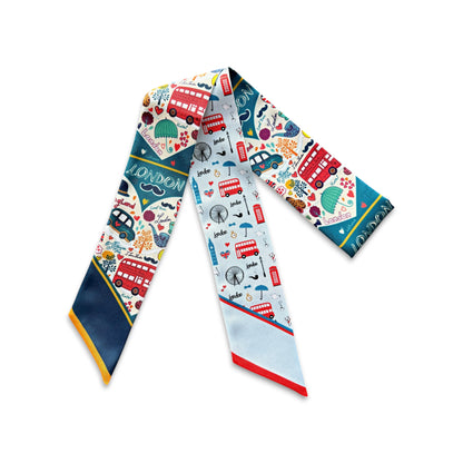 Colorful London skinny scarf featuring iconic red buses, black taxis, British landmarks, and playful travel-inspired illustrations on a light blue background.