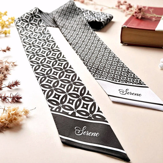 Personalised black and white satin twilly scarf displayed flat, showcasing detailed Indonesian Kawung patterns and elegant script lettering.