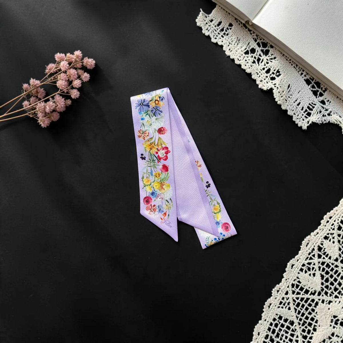 Personalised lilac floral handbag scarf decorated with colourful botanical illustrations, displayed with delicate lace and dried flowers.
