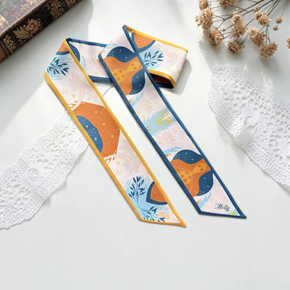 Personalized skinny twilly scarf featuring orange and navy blue abstract patterns, delicate botanical illustrations, yellow borders, and custom Molly lettering on both pointed ends.