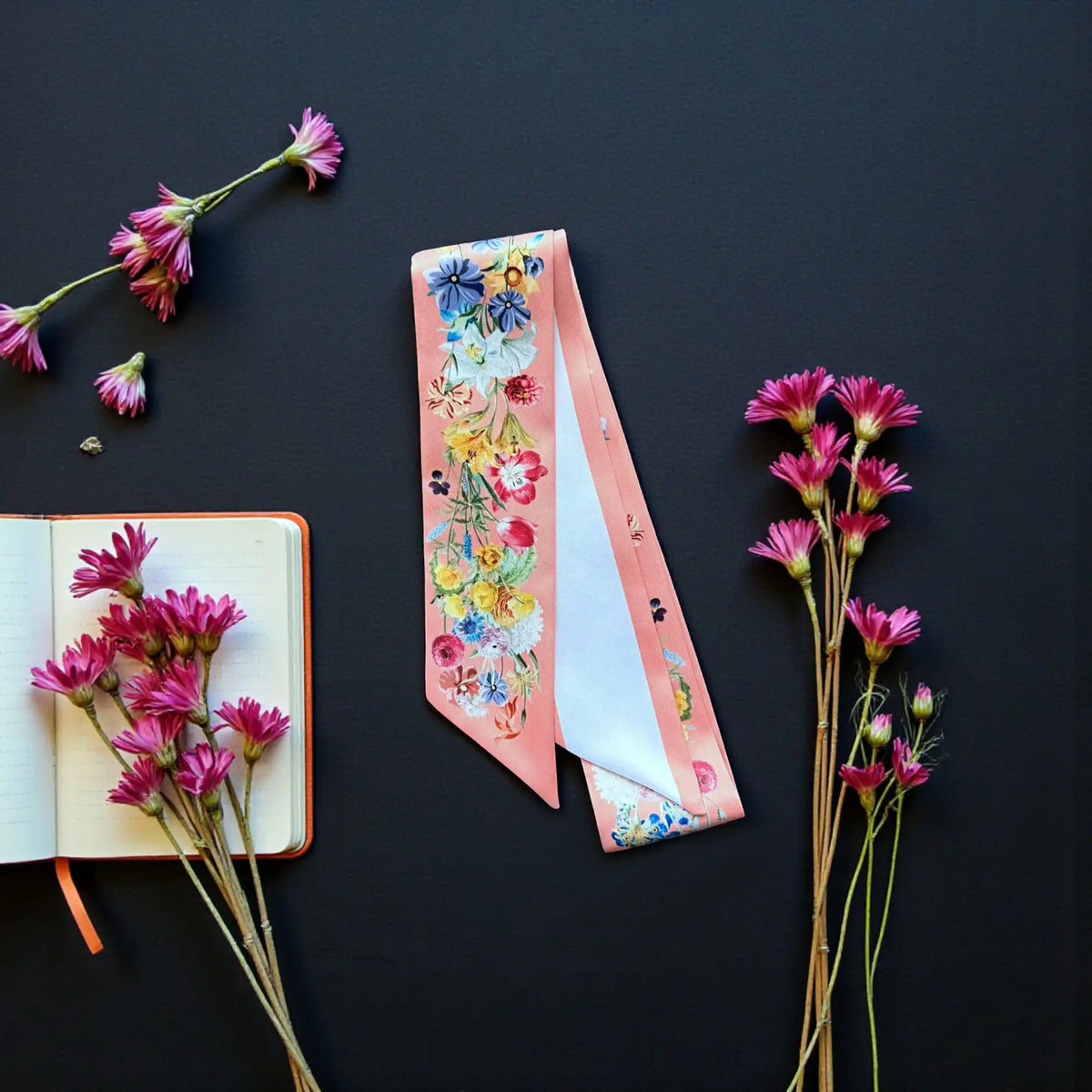 Peach floral handbag scarf decorated with romantic garden blooms and personalised lettering, arranged beside a small notebook and flowers.