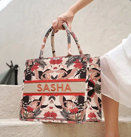 Structured personalized canvas book tote with embroidered name and elegant tropical wildlife print featuring cranes and florals.