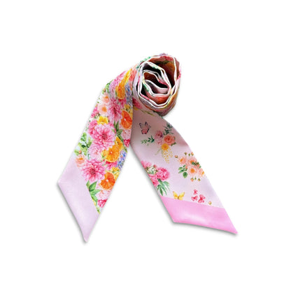 Rolled pink twilly scarf featuring vibrant garden flowers, green foliage, citrus accents and butterflies