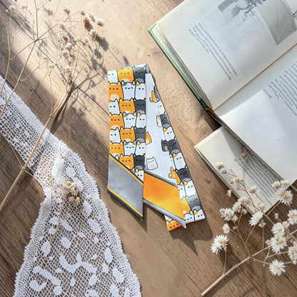 Playful cat lovers twilly scarf featuring two coordinating illustrated cat patterns with orange and grey accents.