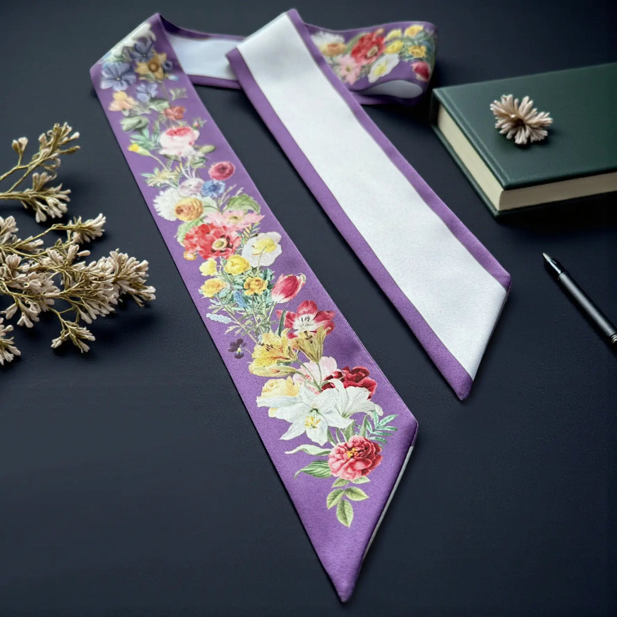 Elegant purple floral twilly scarf with delicate roses, daisies, and garden flowers, featuring a white reverse side and purple trim.