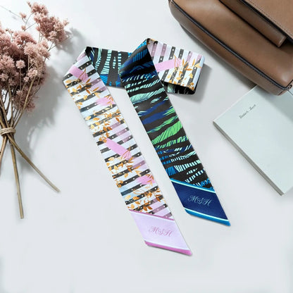Skinny scarves featuring abstract botanical leaf designs in pink, gold, navy, blue, and green.