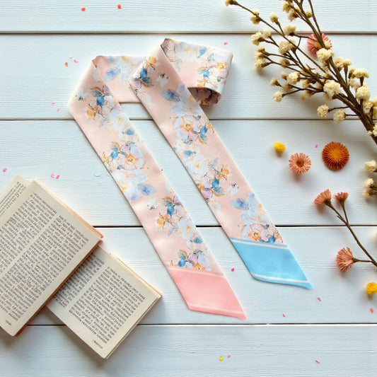 Elegant twilly scarf with soft pastel floral pattern in blush pink and light blue tones