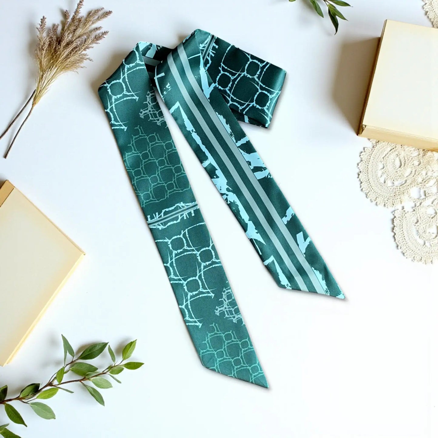 Elegant twilly scarf in deep green tones with subtle geometric pattern and striped detail in a modern design