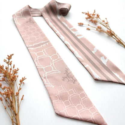 Skinny twilly scarf featuring abstract geometric shapes and stripes in muted blush pink tones