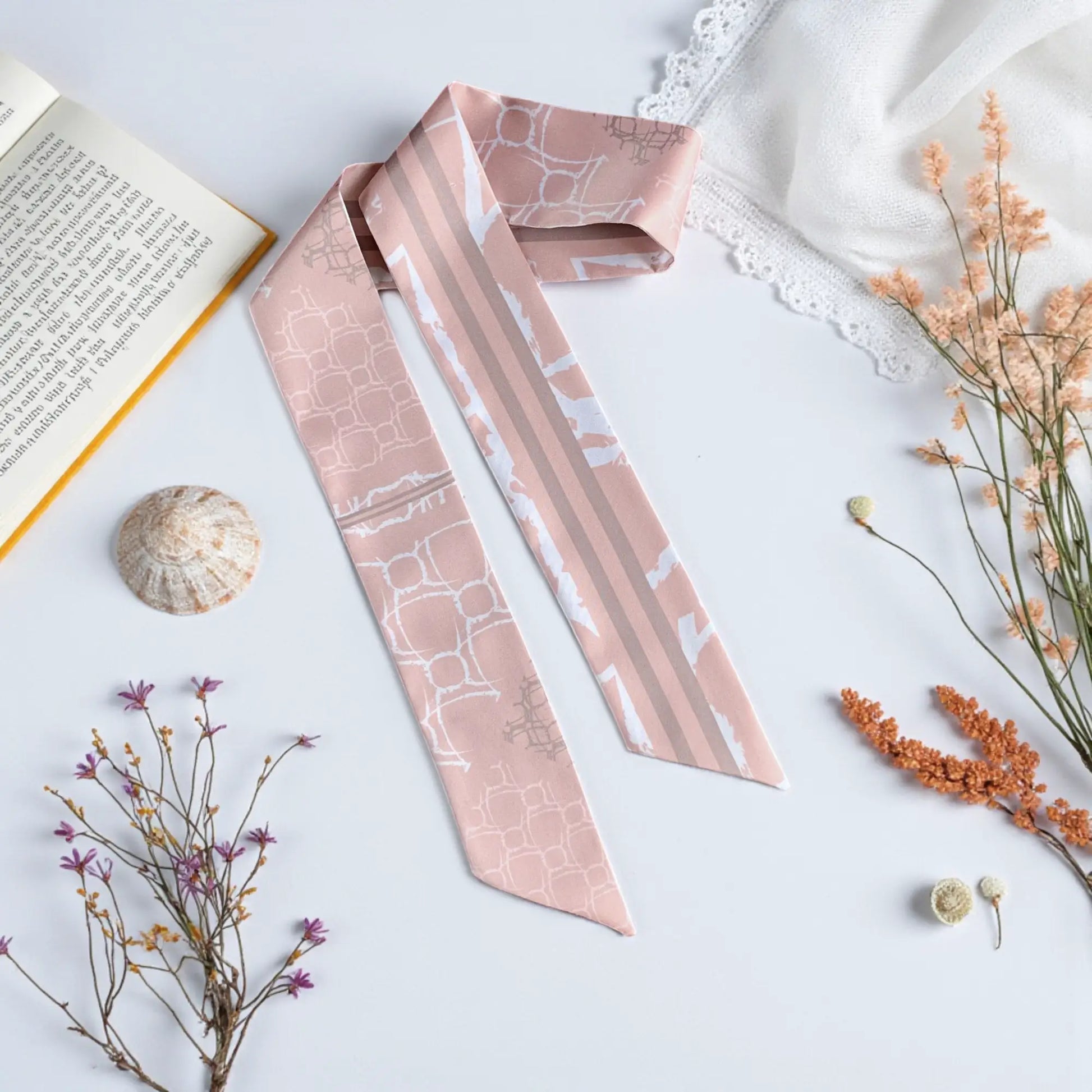 Elegant twilly scarf in soft nude pink with subtle geometric pattern and striped detail in a minimal design