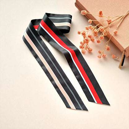 Black skinny scarf with bold red, white, and beige stripe accents in elegant satin finish.