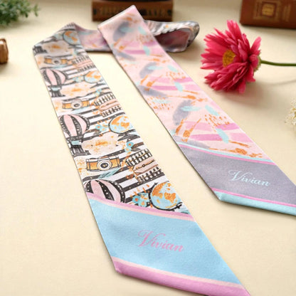Elegant satin skinny scarf showcasing illustrated travel elements, soft pastel colors, and a luxurious double-sided finish.