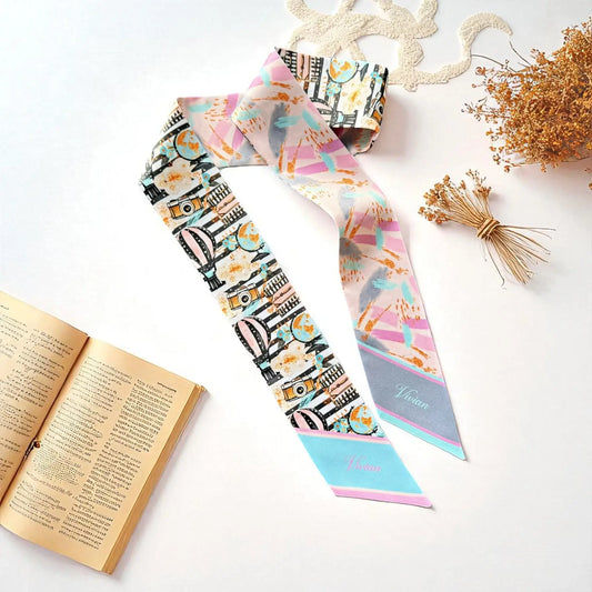 Personalized skinny satin scarf featuring a whimsical travel-inspired illustration with pastel pink, turquoise, and gold accents.