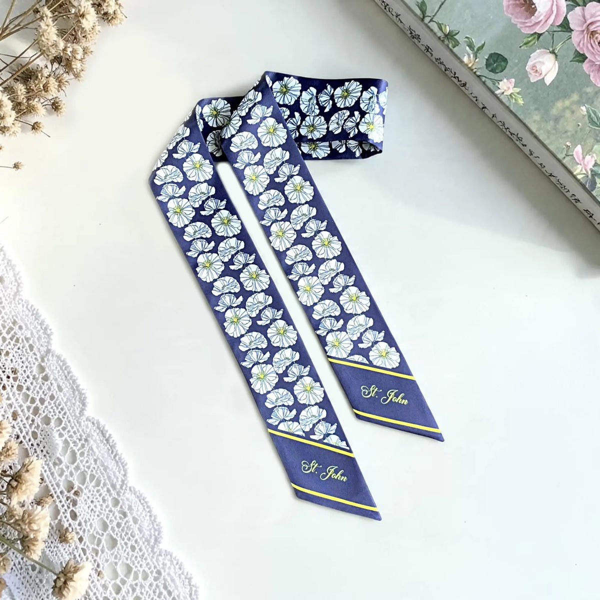 Personalized navy blue skinny scarf featuring delicate white floral prints, yellow accents, and custom St. John lettering on both pointed ends.