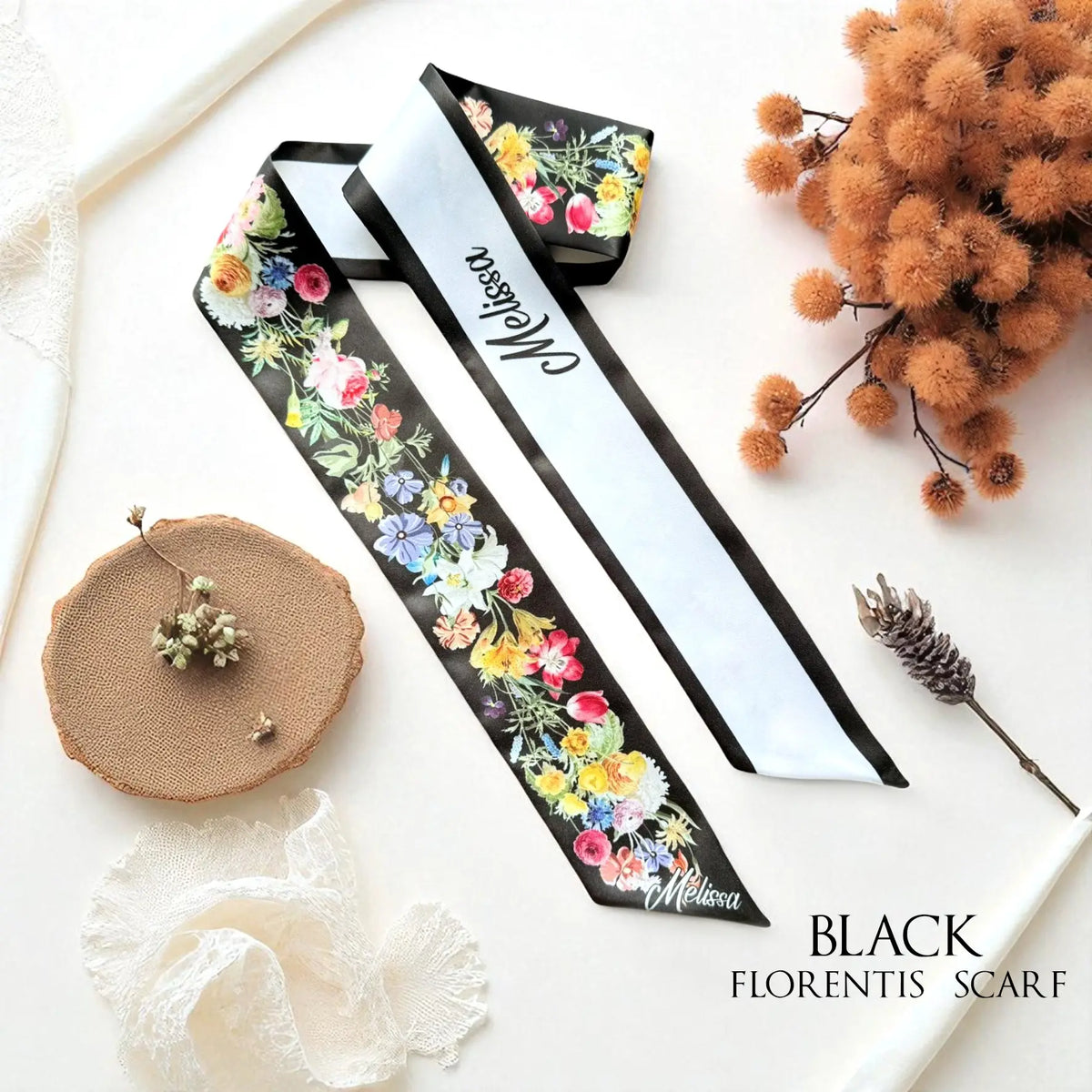 Black personalised skinny scarf with vibrant watercolour roses, daisies, and wildflowers, featuring a white reverse side with custom lettering.