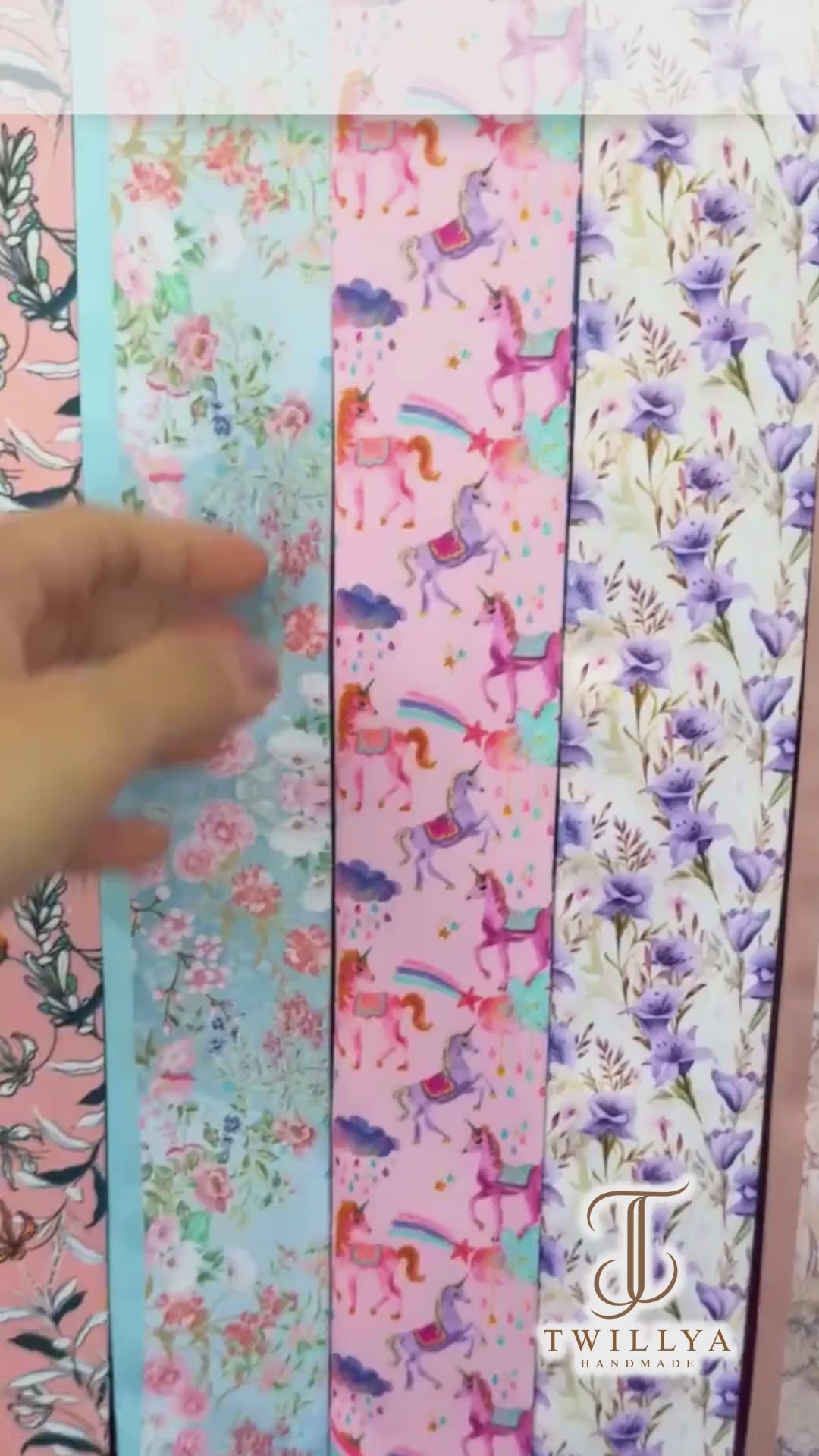 Close-up video showcasing personalised unicorn twilly scarves in pink and navy blue, featuring magical rainbow prints, colourful unicorn illustrations, and custom name details.